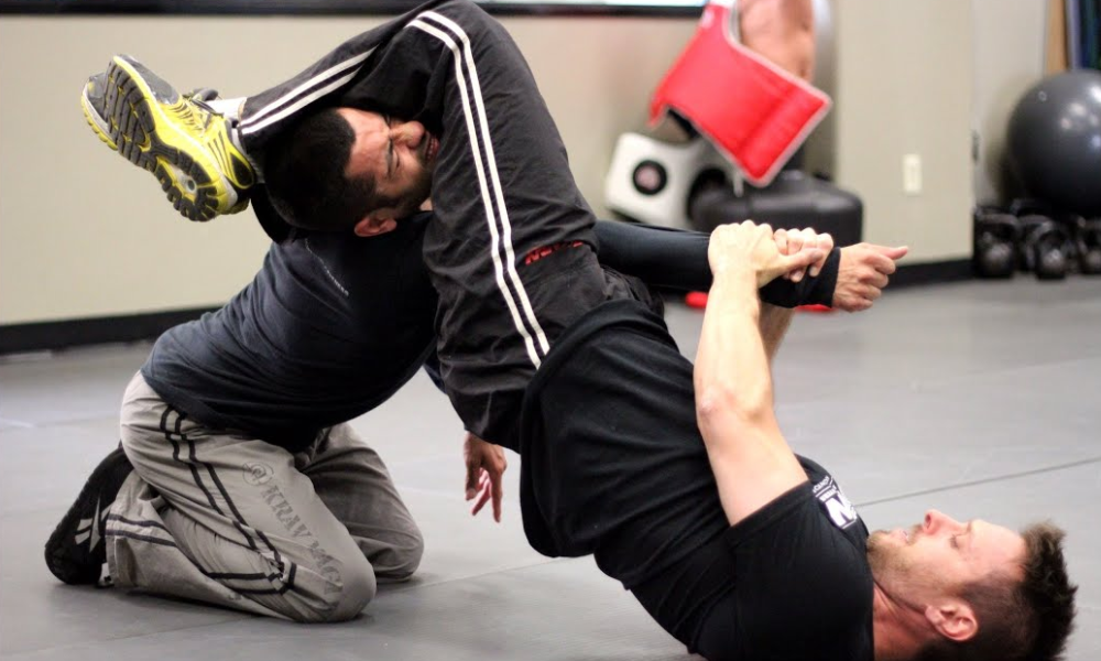 Two men in their dojo, with one trapping the other in an arm lock.