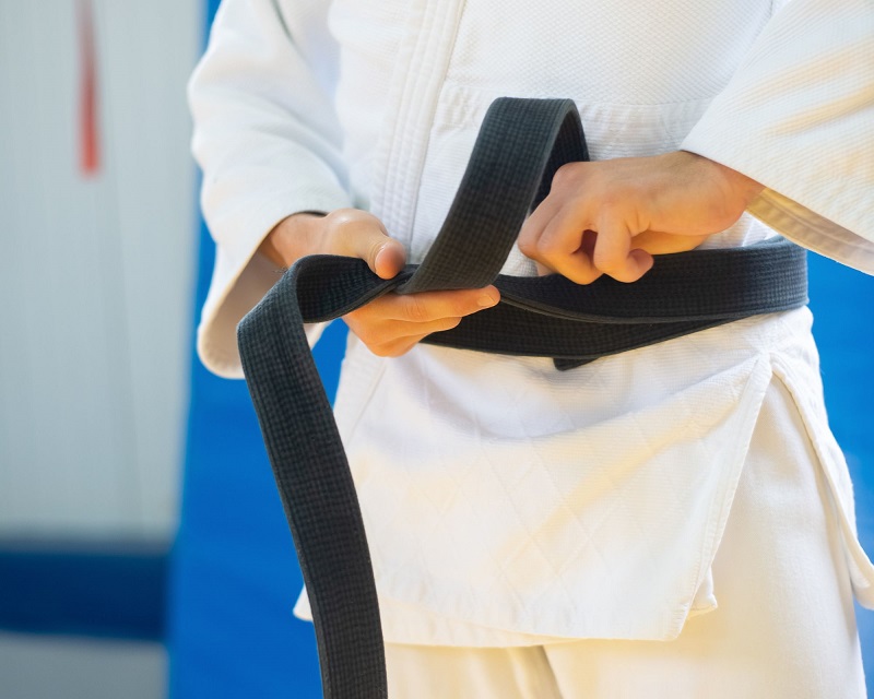 A man wearing a black belt to motivate readers trying to attain one for themselves.