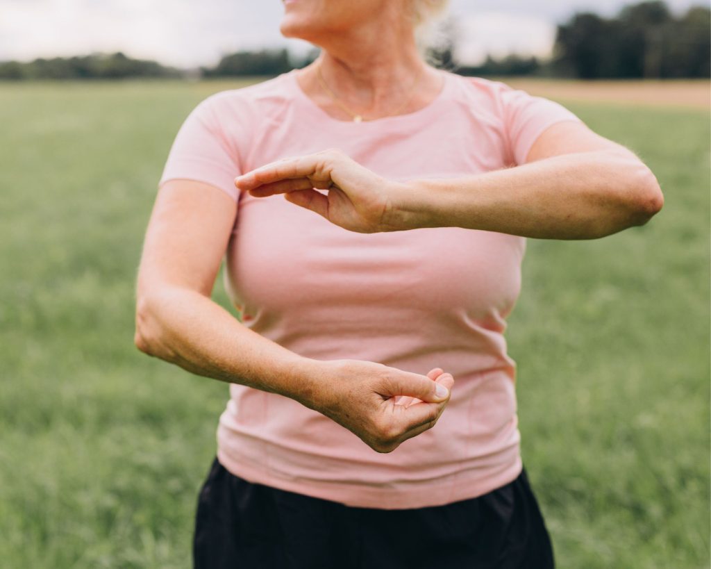 An elderly woman practicing moving meditation with tai chi.