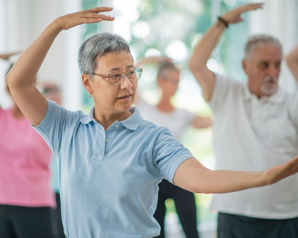 An elderly woman doing her best to embody the principles of tai chi.