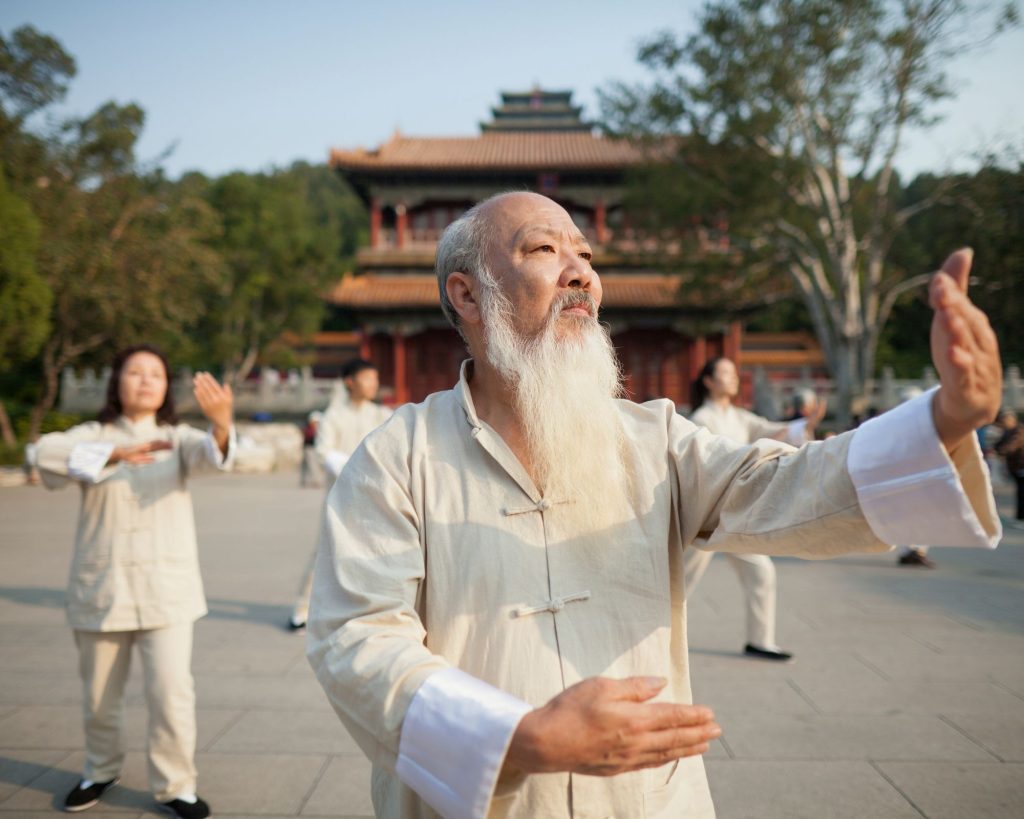 An older man practicing ancient tai chi movements.