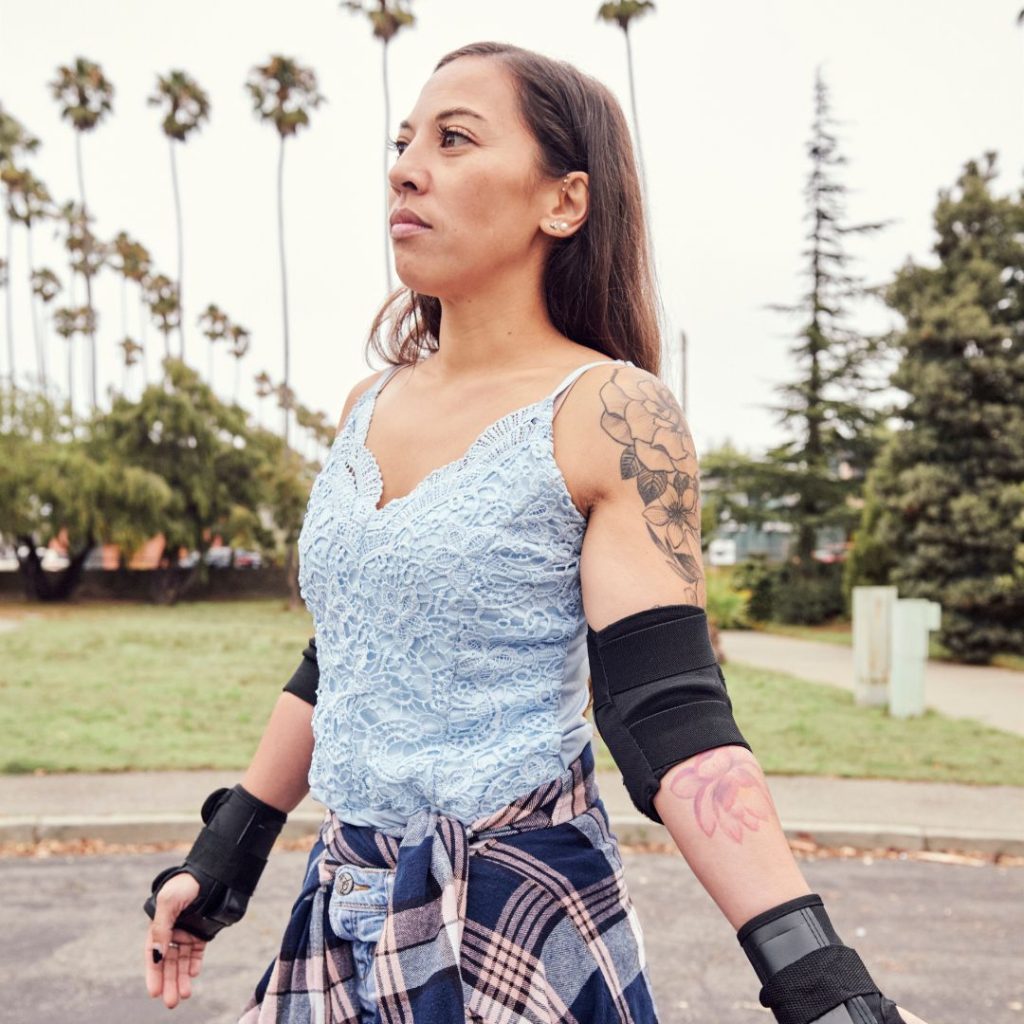 A woman with elbow pads and gloves, which are common protective accessories.