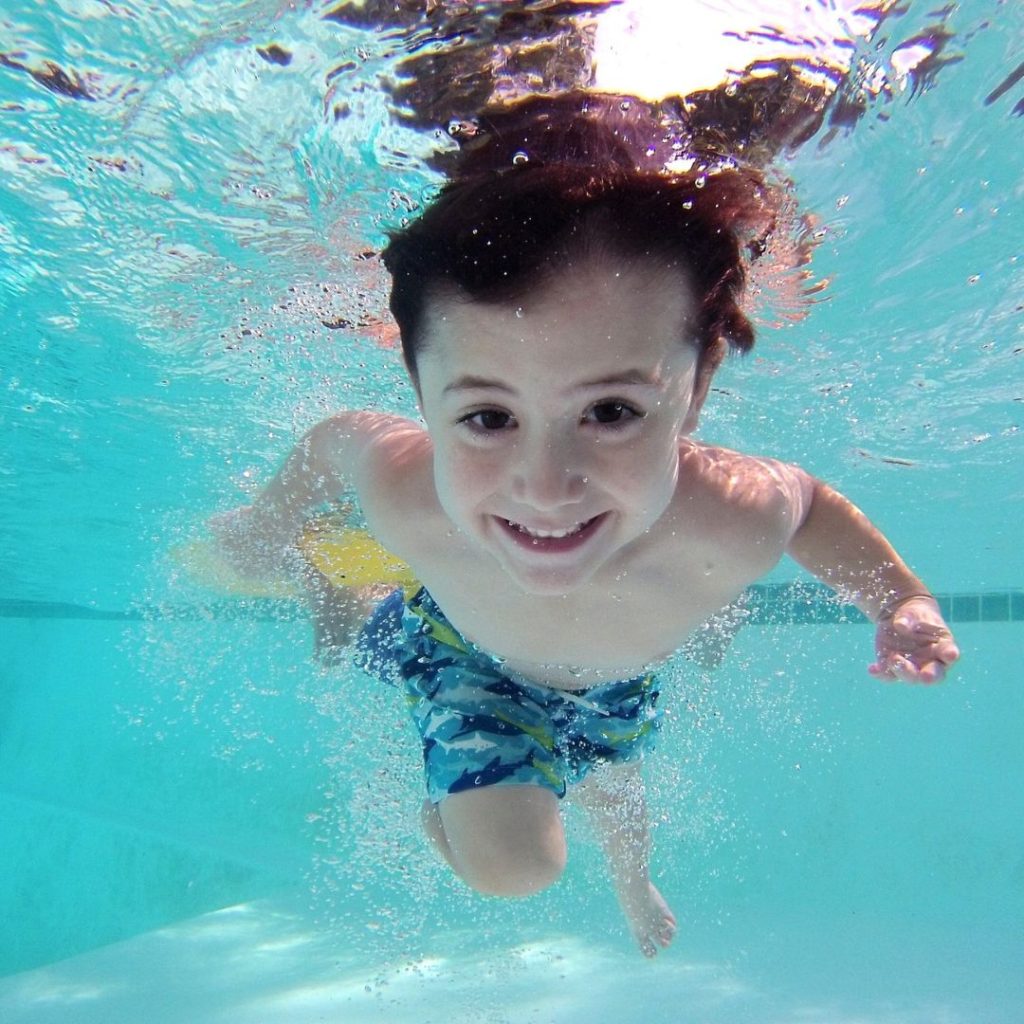 A child happily swimming, which is a good alternative to BJJ for coping with ADHD.